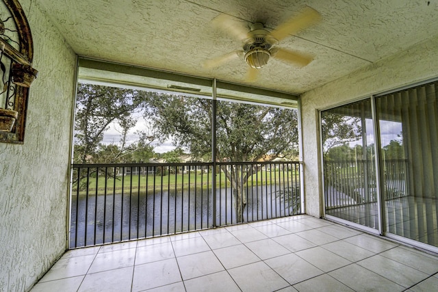 unfurnished sunroom with a water view and ceiling fan