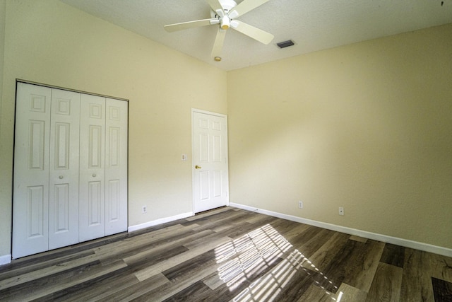 unfurnished bedroom featuring dark wood-type flooring, a closet, and ceiling fan