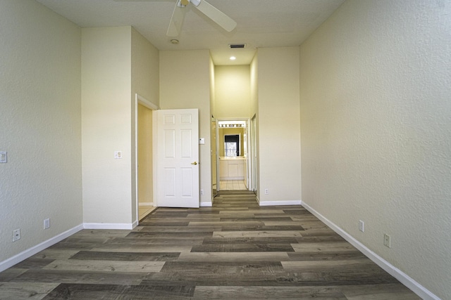 unfurnished room with dark hardwood / wood-style flooring, ceiling fan, and a high ceiling