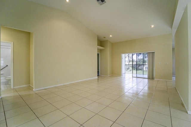 empty room with high vaulted ceiling and light tile patterned flooring