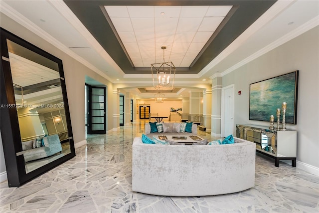 interior space with a chandelier, baseboards, marble finish floor, a tray ceiling, and decorative columns