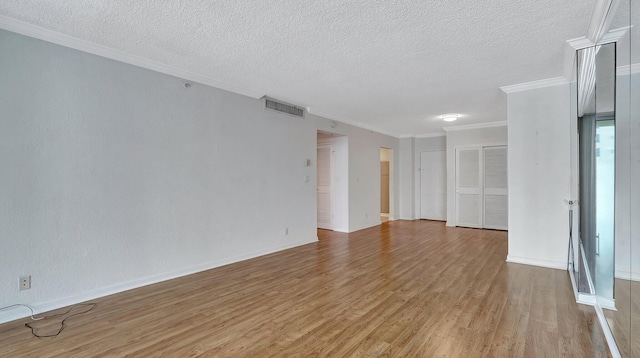 spare room featuring a textured ceiling, crown molding, and hardwood / wood-style floors