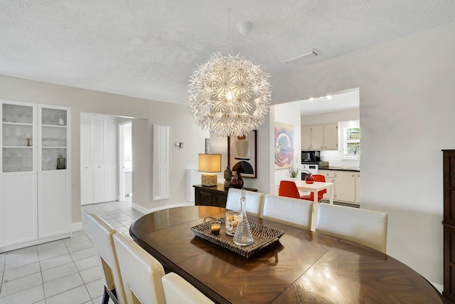 tiled dining room with a notable chandelier and a textured ceiling