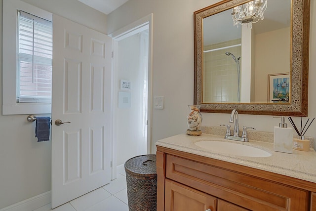 bathroom with tile patterned floors, vanity, tiled shower, and an inviting chandelier