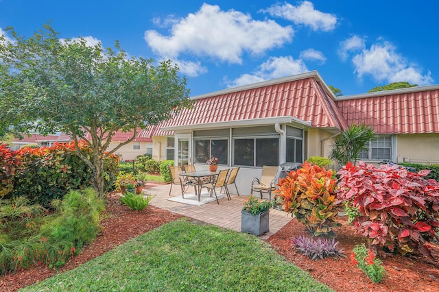 rear view of house featuring a sunroom and a patio