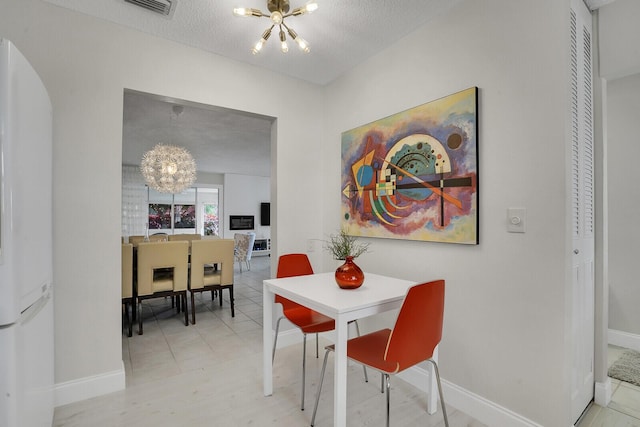 dining space with a textured ceiling and a chandelier