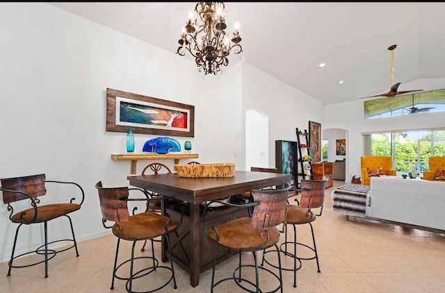 dining space with a high ceiling, ceiling fan with notable chandelier, and light tile patterned floors