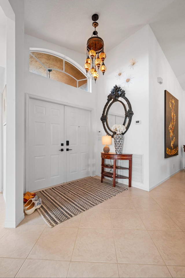 tiled entrance foyer featuring an inviting chandelier and a high ceiling