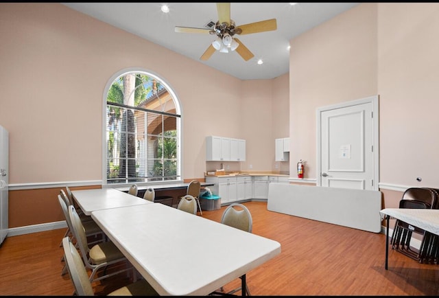 kitchen featuring high vaulted ceiling, light hardwood / wood-style floors, white cabinets, and ceiling fan