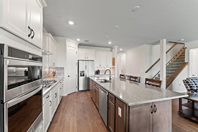 kitchen with stainless steel appliances, white cabinets, and a kitchen island with sink