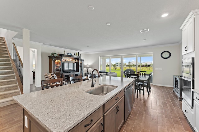 kitchen with a center island with sink, sink, crown molding, appliances with stainless steel finishes, and white cabinets