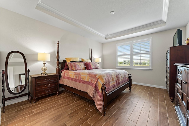 bedroom featuring hardwood / wood-style flooring, a tray ceiling, and crown molding