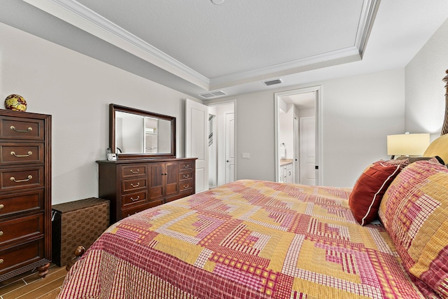 bedroom with crown molding, a raised ceiling, and ensuite bath