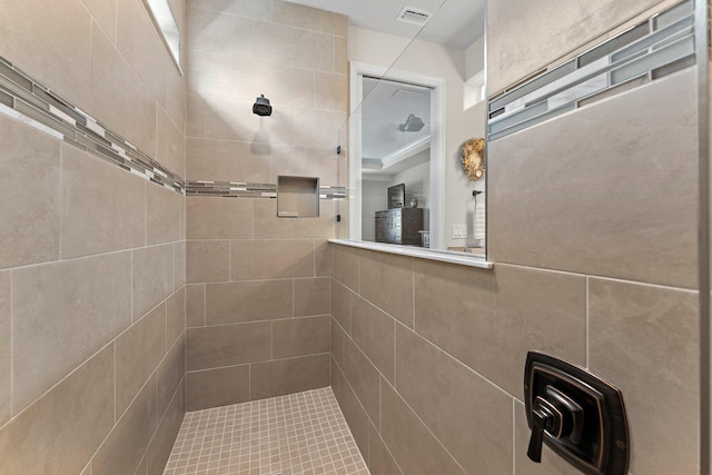 bathroom with tiled shower and ornamental molding