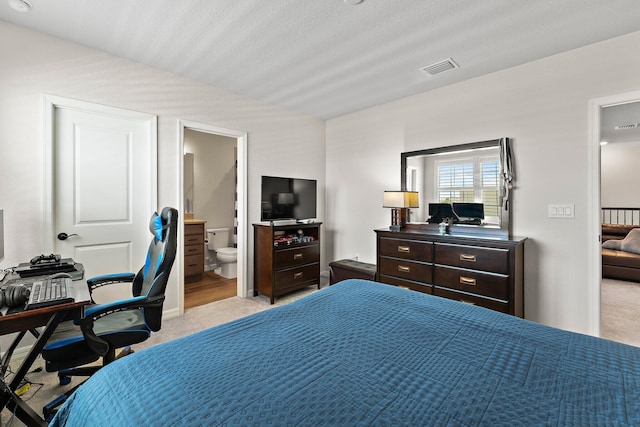 bedroom with light colored carpet, connected bathroom, and a textured ceiling