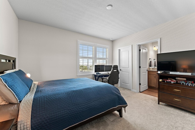 carpeted bedroom featuring a textured ceiling and ensuite bathroom