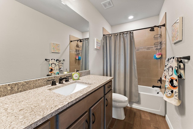 full bathroom with hardwood / wood-style floors, toilet, vanity, and shower / tub combo