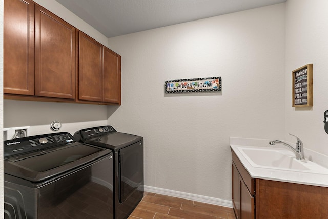 washroom with cabinets, washing machine and clothes dryer, and sink