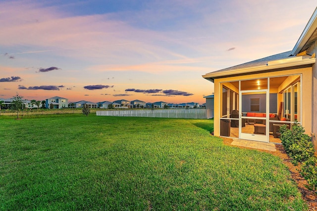 yard at dusk featuring a sunroom