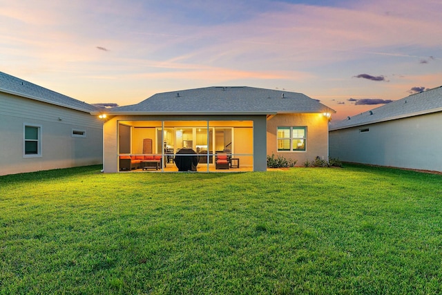 back house at dusk with a lawn and a patio