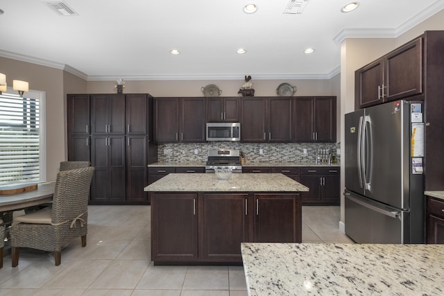 kitchen with a center island, stainless steel appliances, light tile patterned floors, crown molding, and dark brown cabinets