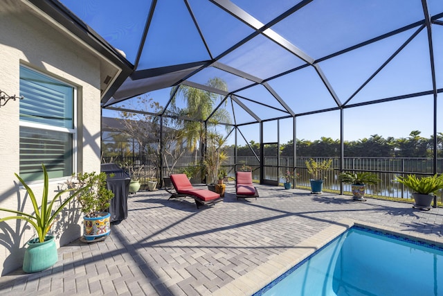 view of swimming pool featuring a patio area, glass enclosure, and a water view