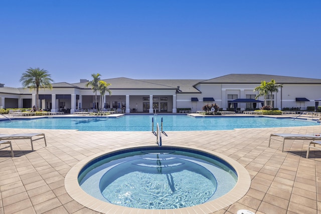 view of swimming pool with a hot tub and a patio