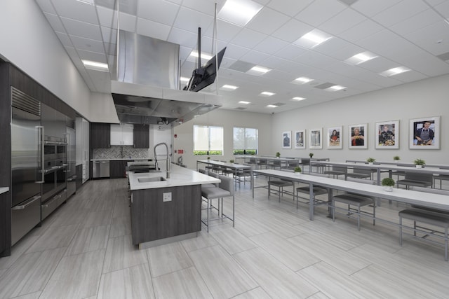 kitchen featuring a spacious island, a kitchen bar, decorative backsplash, appliances with stainless steel finishes, and sink