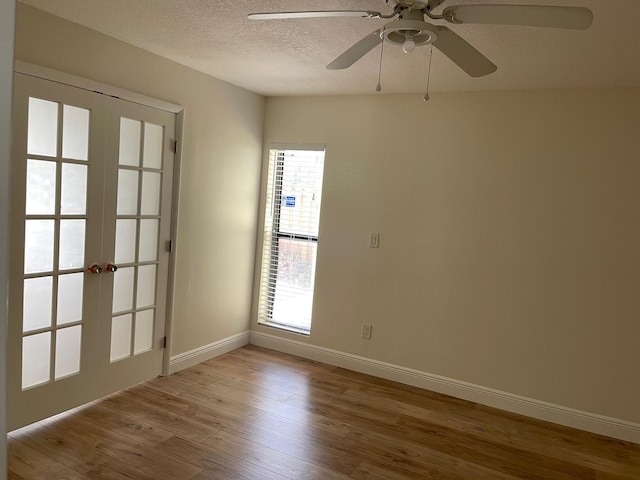 empty room featuring ceiling fan, a textured ceiling, light hardwood / wood-style flooring, and french doors