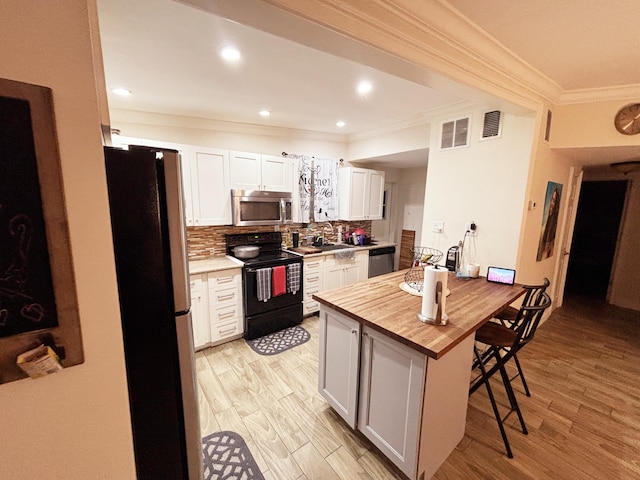 kitchen with white cabinetry, wood counters, appliances with stainless steel finishes, and backsplash