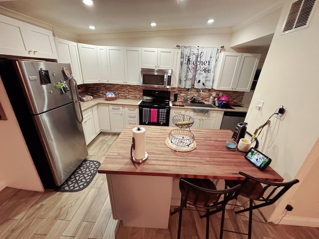 kitchen featuring sink, tasteful backsplash, wooden counters, appliances with stainless steel finishes, and white cabinets