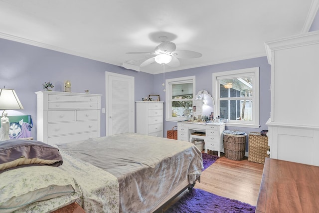 bedroom with ceiling fan, ornamental molding, a closet, and hardwood / wood-style flooring