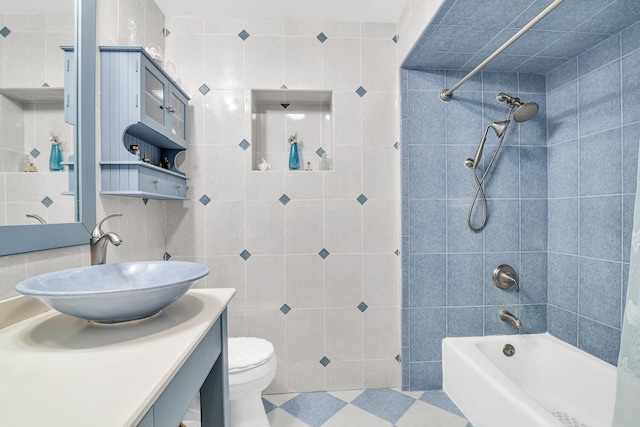 full bathroom with toilet, tiled shower / bath combo, tile walls, and vanity