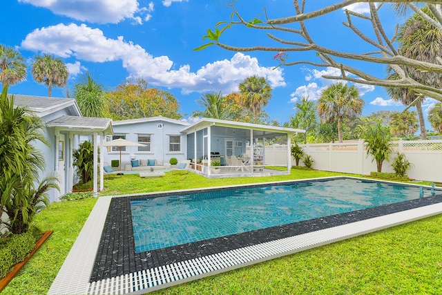 back of property with a fenced in pool, a sunroom, and a lawn