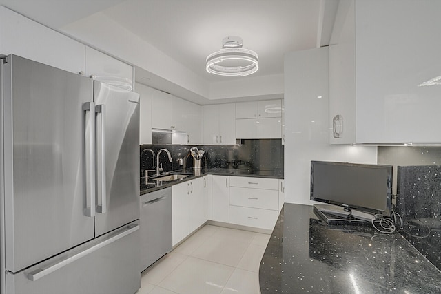 kitchen with appliances with stainless steel finishes, white cabinetry, tasteful backsplash, sink, and light tile patterned flooring