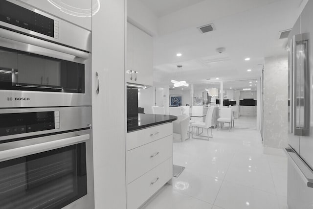 kitchen with light tile patterned floors, pendant lighting, white cabinets, and stainless steel double oven