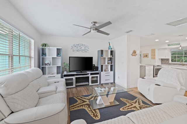 living room with light hardwood / wood-style floors, sink, and ceiling fan