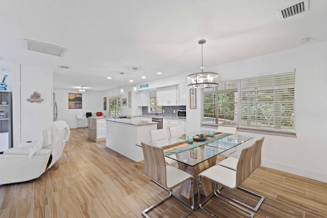 dining space with plenty of natural light, an inviting chandelier, and light hardwood / wood-style flooring