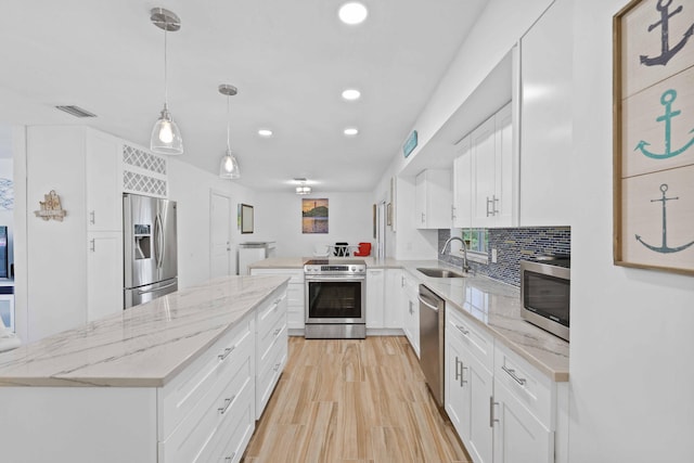 kitchen featuring hanging light fixtures, white cabinets, appliances with stainless steel finishes, and sink