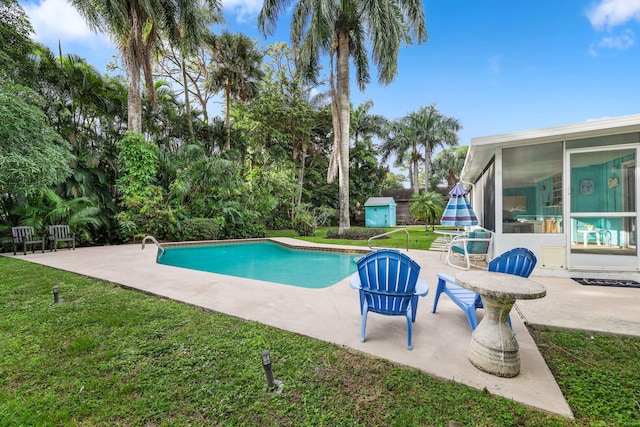 view of swimming pool featuring a storage unit, a patio area, a yard, and a sunroom