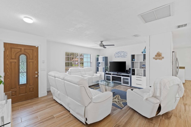 living room featuring ceiling fan and a textured ceiling