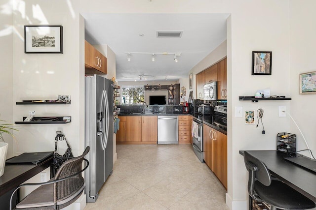 kitchen with sink, kitchen peninsula, light tile patterned floors, and stainless steel appliances