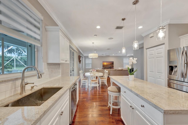 kitchen with light stone counters, appliances with stainless steel finishes, sink, and white cabinets