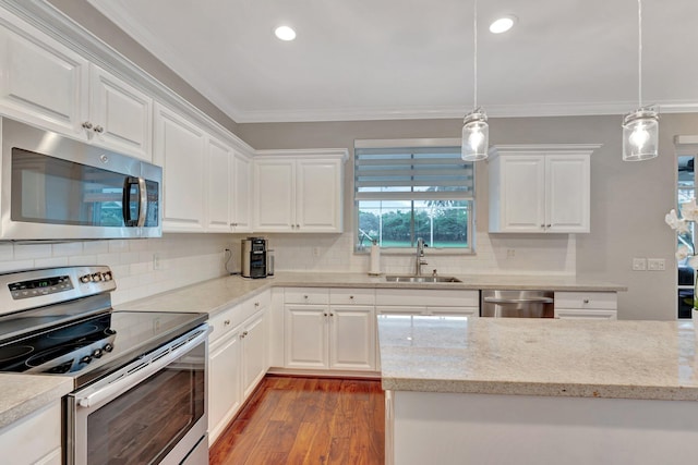 kitchen featuring sink, decorative light fixtures, ornamental molding, appliances with stainless steel finishes, and white cabinets