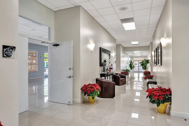 corridor featuring light tile patterned flooring and a drop ceiling