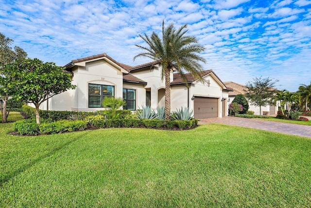 mediterranean / spanish house with a garage, a tile roof, decorative driveway, a front lawn, and stucco siding