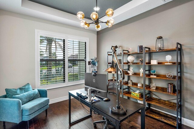 office featuring a raised ceiling, a notable chandelier, and dark hardwood / wood-style flooring