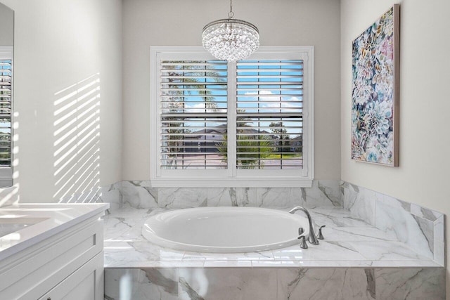 bathroom with tiled tub, vanity, and an inviting chandelier