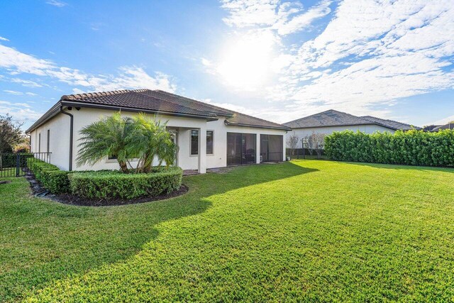 back of property with a sunroom and a lawn