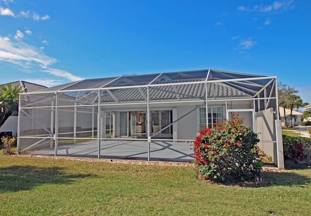 back of house with a lanai, a lawn, and a patio